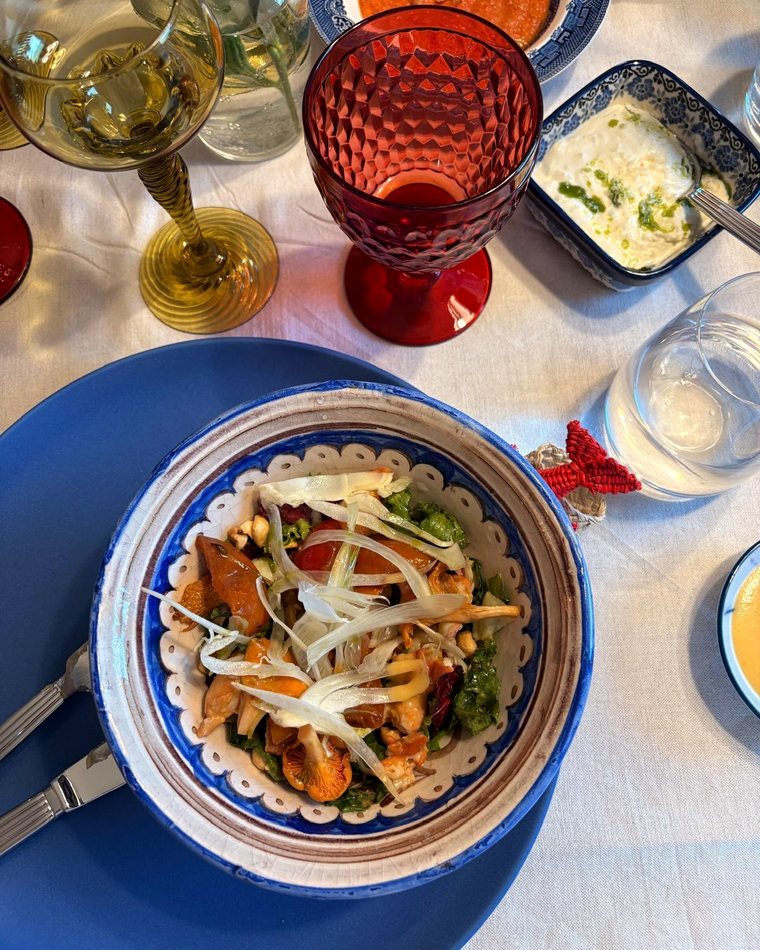 Upplagd rätt vid ett dukat bord med tänt ljus och vitt vin